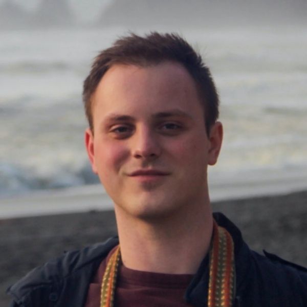 Outdoor headshot of a person photographed at a coastal location with the sea in the background.